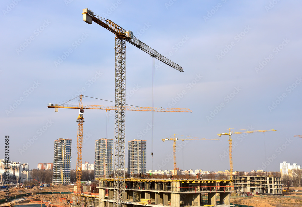 View of a large construction site. Tower cranes in action. Housing renovation concept. Crane during formworks. Construction the buildings and multi-storey residential homes View of a large construction site. Tower cranes in action. Housing renovation concept. Crane during formworks. Construction the buildings and multi-storey residential homes