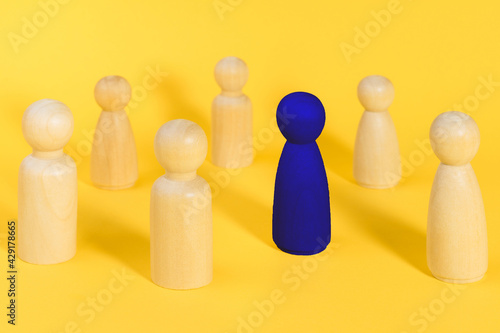 Blue wooden figure among many yellow figures. Standing out from crowd  individuality  leadership  be unique minimal idea . Think different business creative concept