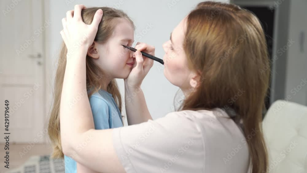 Mom does makeup daughter, draws arrows on the eyelids to perform on stage. preparing the child for the concert. Mom does makeup daughter, draws arrows on the eyelids to perform on stage. preparing the child for the concert.
