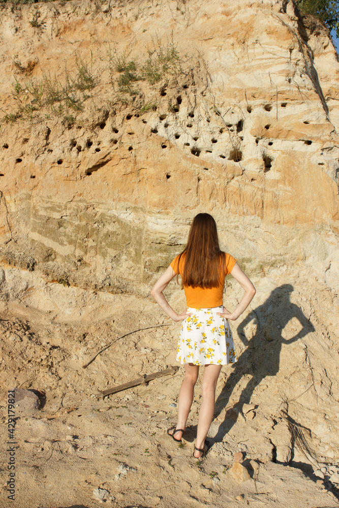 Swifts and swallows nests in a sandy quarry. A young beautiful girl is watching the life of birds.