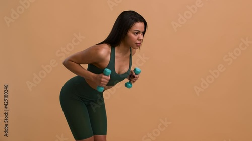 Black Lady Performing Dumbbell Triceps Kickback Exercise Over Beige Background
