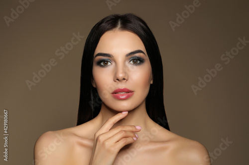 Beautiful young woman with evening makeup on brown background. Eye shadow product