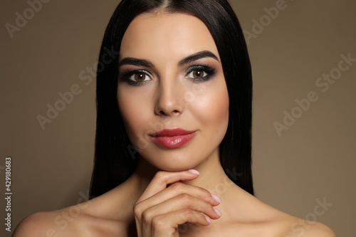 Beautiful young woman with evening makeup on brown background. Eye shadow product