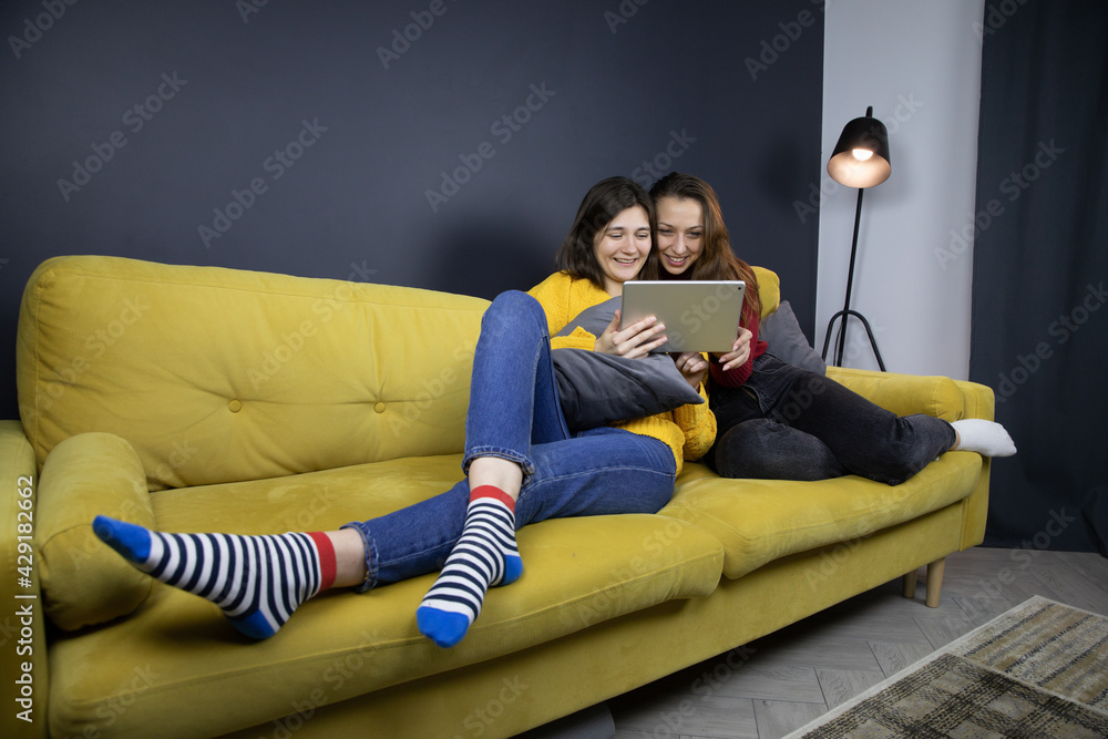 two pretty long haired brunette girls laugh watching comedy or