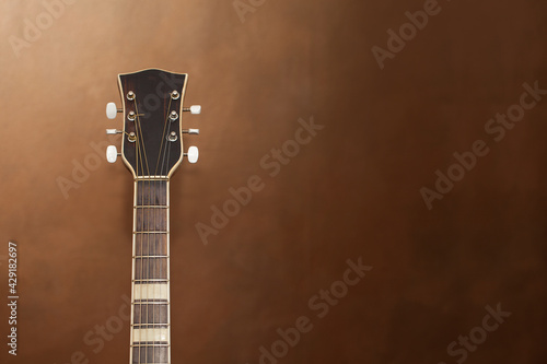 Fragment of a neck with the headstock of an acoustic guitar on a blurred background.