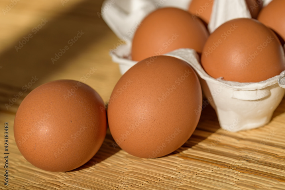 Chicken eggs in a paper carton, straw mat background Chicken eggs in a paper carton, straw mat background