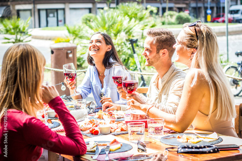 Multiracial people drinking red wine at open bar restaurant - Group of friends laughing having fun dining together outdoor -  Bright filter