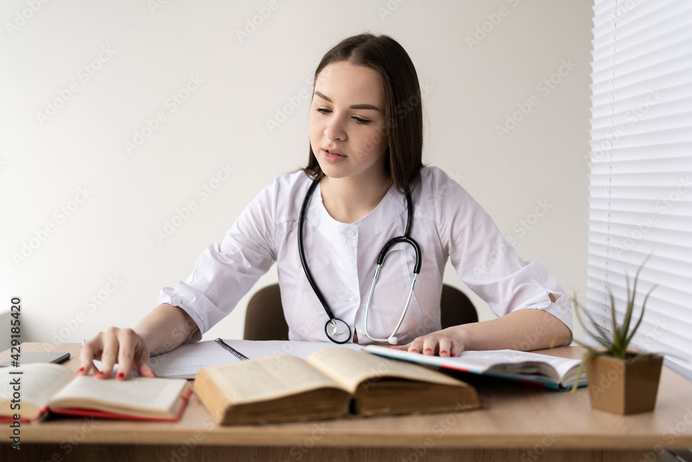 Portrait of Caucasian female doctor reading medical books in search of information about rare diseases science, medicine and pharmacy concept. Portrait of Caucasian female doctor reading medical books in search of information about rare diseases science, medicine and pharmacy concept.
