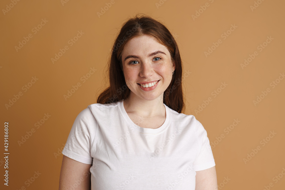 Smiling young plus size woman posing over beige Smiling young plus size woman posing over beige