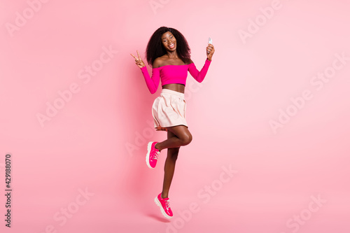 Full size photo of optimistic brunette nice lady jump show v-sign do selfie wear pink top skirt isolated on pastel color background