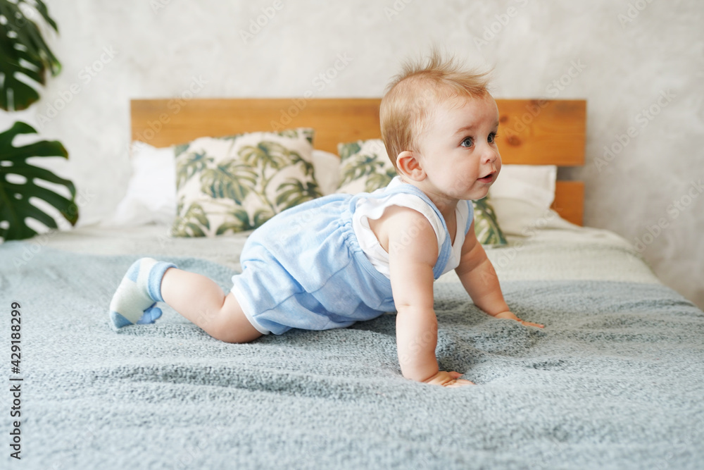 Adorable baby boy in white sunny bedroom. Textile and bedding for kids. Family morning at home Adorable baby boy in white sunny bedroom. Textile and bedding for kids. Family morning at home