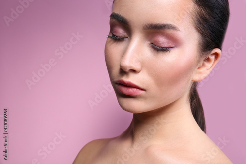 Portrait of young beautiful woman with perfectly clean face skin wearing professional make up. Female with long black hair tied in a ponytail. Close up, copy space background.