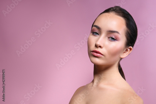 Portrait of young beautiful woman with perfectly clean face skin wearing professional make up. Female with long black hair tied in a ponytail. Close up, copy space background.