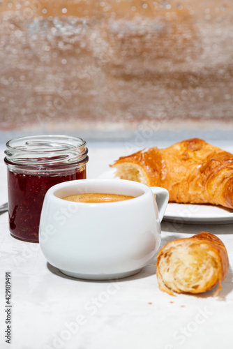 cup of espresso and fresh croissants  berry jam for breakfast on white table  closeup