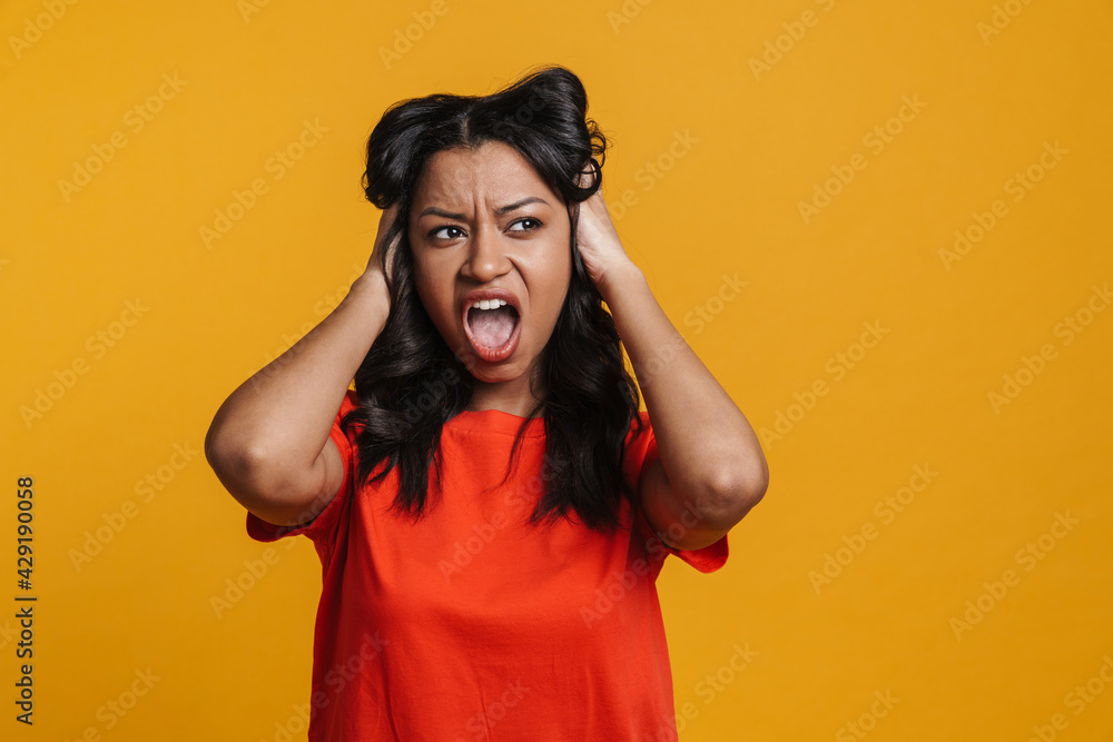 Angry black woman holding her head while screaming at camera Angry black woman holding her head while screaming at camera