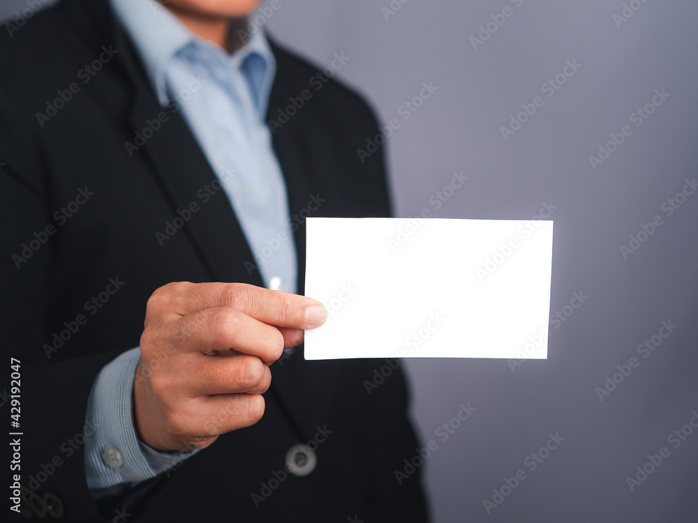 Businessman showing a blank white business card while standing with a gray background. Close-up photo. Space for text. Business and contact concept Businessman showing a blank white business card while standing with a gray background. Close-up photo. Space for text. Business and contact concept