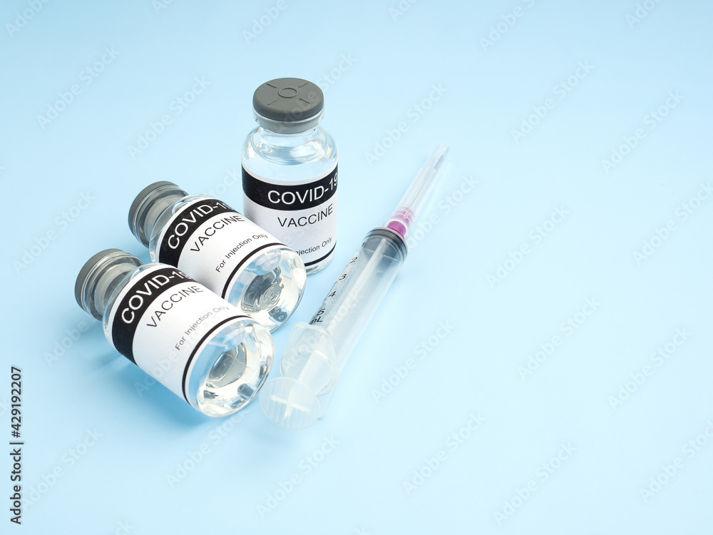 COVID-19 vaccine in glass bottles with a syringe placed on a light blue background. Vaccine for immunization, and treatment from coronavirus infection. Top view. Concept of medical and healthcare COVID-19 vaccine in glass bottles with a syringe placed on a light blue background. Vaccine for immunization, and treatment from coronavirus infection. Top view. Concept of medical and healthcare