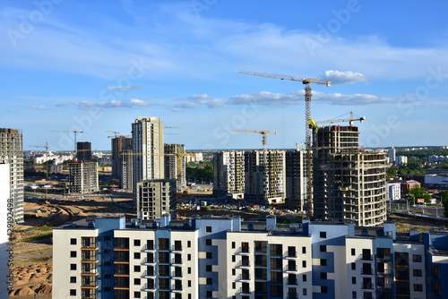 Tower cranes in action on blue sky background. Drone view on construction of new multi-storey buildings. Residential building is being constructed use of crane. Pouring of concrete in formwork