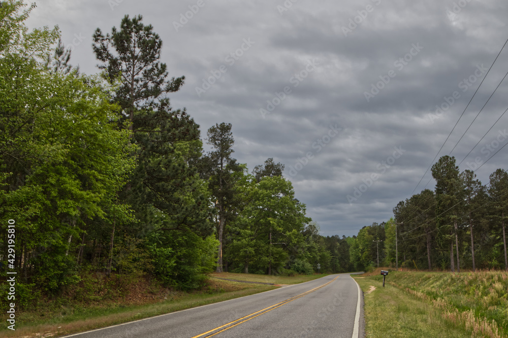 Fototapeta premium Long country road on a storm cloud day mailbox