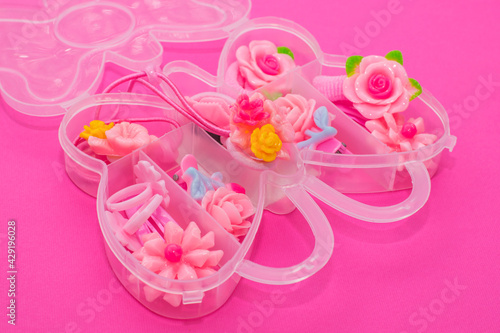 Cute girly hair accessories in a butterfly shaped plastic box. Hair ties, hairpins made of plastic in the shape of flowers and cute animals.