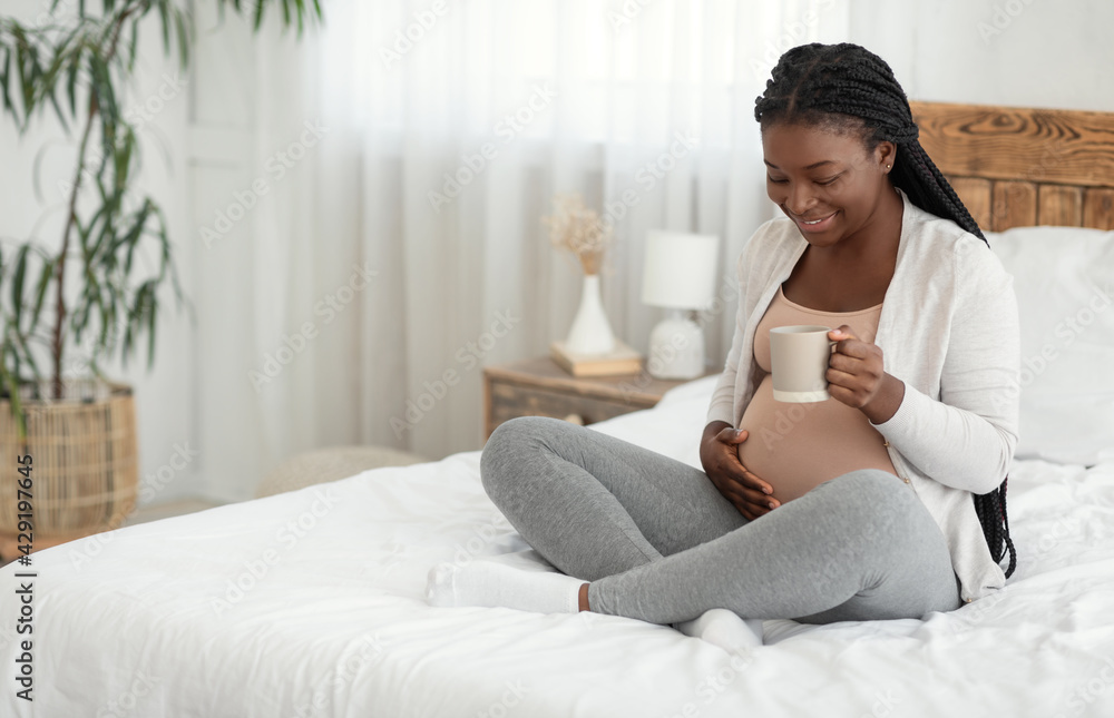 Smiling Black Expectant Mother Relaxing At Home With Cup Of Herbal Tea Smiling Black Expectant Mother Relaxing At Home With Cup Of Herbal Tea