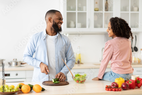 Black dad cooking together with daughter in the kitchen