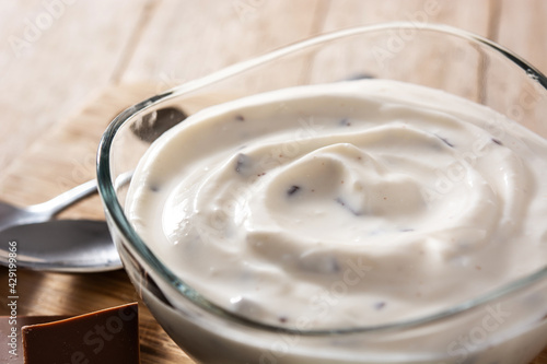 Stracciatella yogurt in transparent bowl on wooden table 