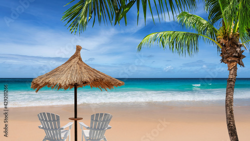 Parasol in tropical Sunny beach with coco palms and beach sunbeds, turquoise sea in tropical island. Summer vacation and tropical beach concept. 