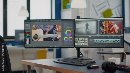 Video production studio with nobody in it and computer with two displays processing video film montage in new software. Empty movie editing creative start up agency with no people