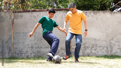 father and son playing soccer in a backyard