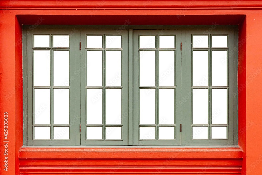 Four bright green wooden windows and red cement wall