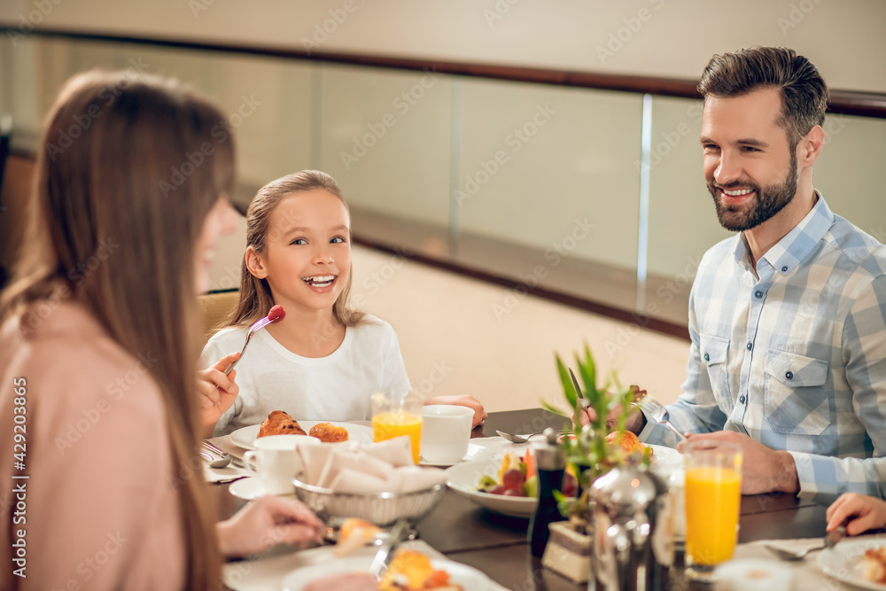Smiling family sitting at the table and looking happy Smiling family sitting at the table and looking happy