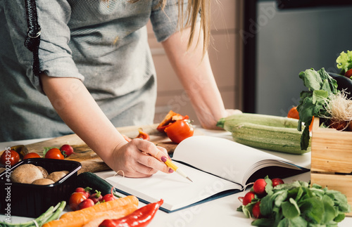 Fotografi Unrecognizable woman is looking for recipes in cookbook