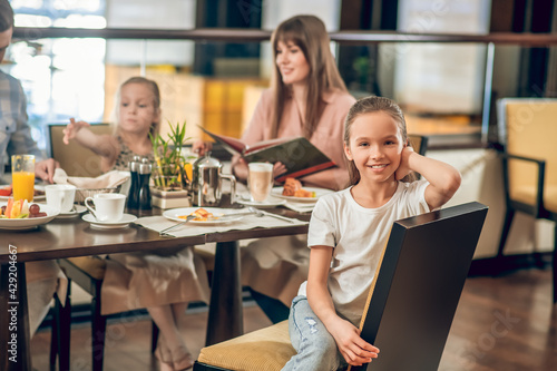 Sweet girl sitting at the table in the restaurant with family