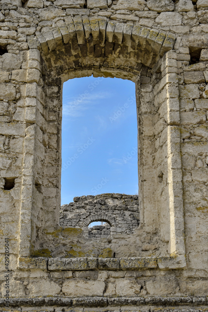 Dilapidated ancient synagogue. View of the sky and the wall through the arched window. The texture of old dilapidated masonry. Stones covered with moss. Rashkov, Moldova. Selective focus.