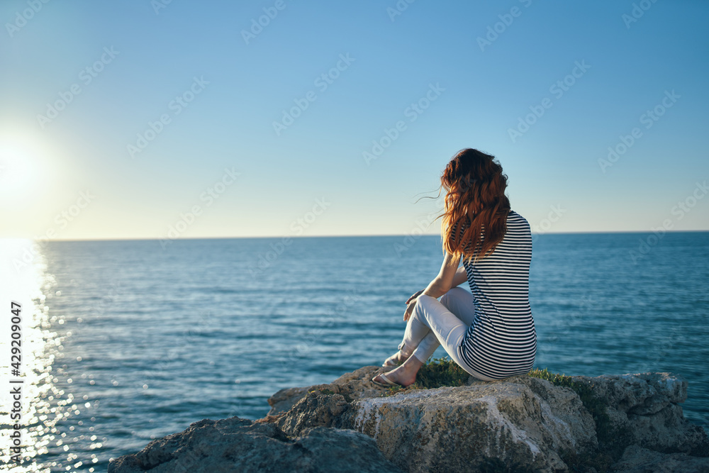 woman on vacation in the mountains near the sea gestures with her hands and sunset summer