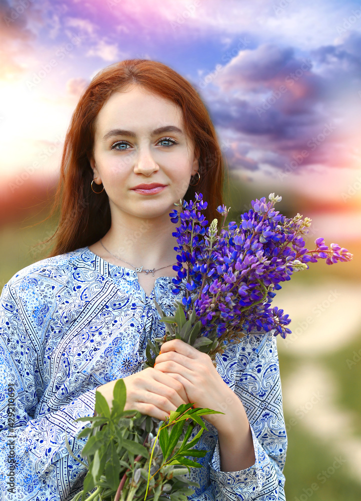 Portrait with a young girl, holding a bouquet of lilac lupins in her hands. Stunning sky and sunset background. Nature. Summer concept. Portrait with a young girl, holding a bouquet of lilac lupins in her hands. Stunning sky and sunset background. Nature. Summer concept.