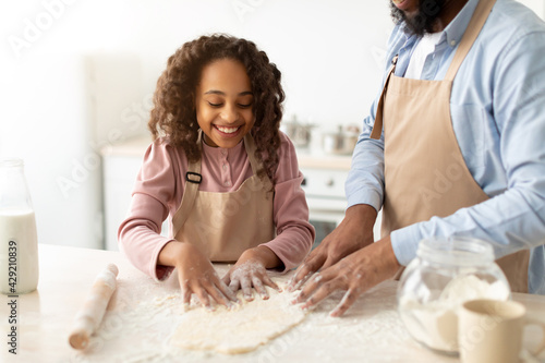 Photography Afro man and his child daughter kneading dough on table
