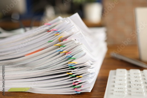 Lot of documents fastened with multicolored paper clips lying on table closeup
