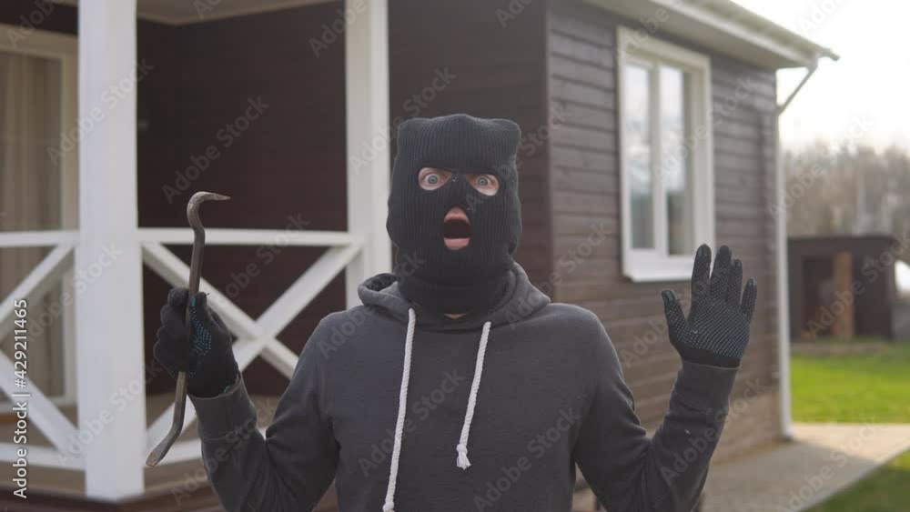 Portrait of thief in black balaclava and gloves raising hands up. Masked robber being arrested. Get Caught Concept. Portrait of thief in black balaclava and gloves raising hands up. Masked robber being arrested. Get Caught Concept.