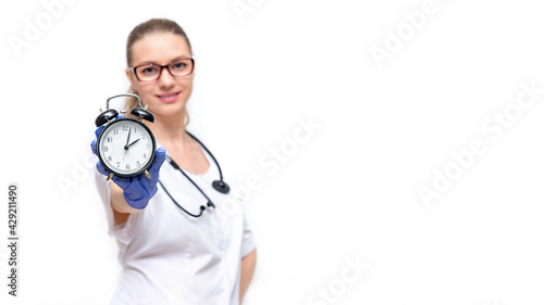 Female doctor in white coat he holds watch in his hand. Time to take care of your health. Isolated on white background. Timely access to doctor, passing medical examinations, prevention of diseases.