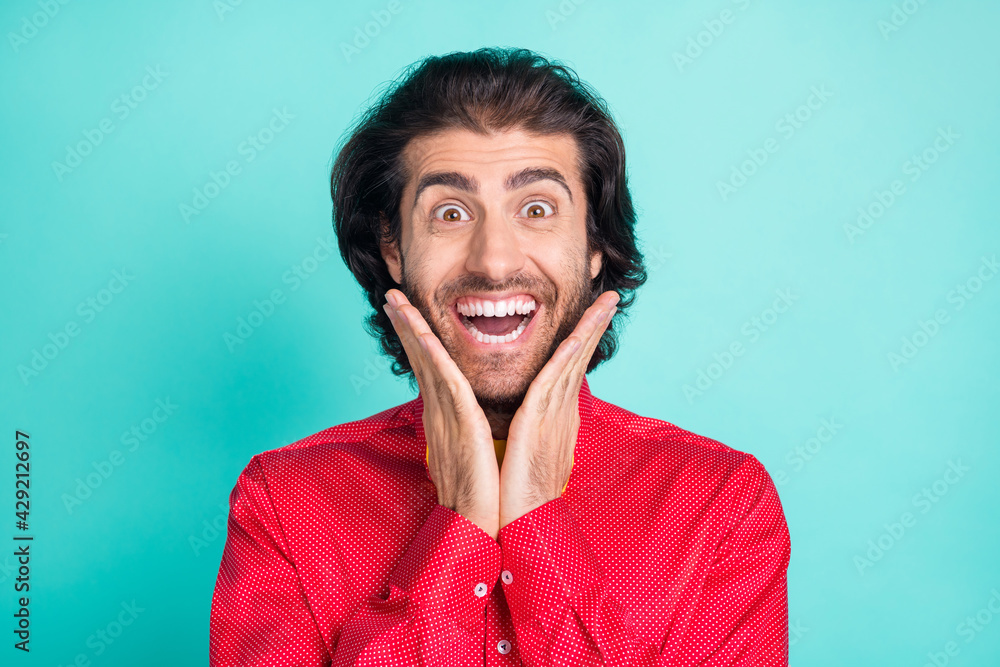 Photo of young crazy smiling cheerful handsome man hold hands cheeks hear good news isolated on turquoise color background Photo of young crazy smiling cheerful handsome man hold hands cheeks hear good news isolated on turquoise color background