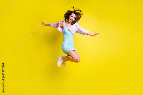 Full length body size view of attractive cheerful wavy-haired girl jumping having fun life isolated over bright yellow color background