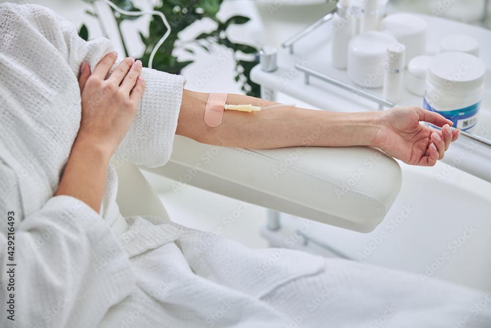 Young female in white bathrobe during medical procedure in beauty clinic