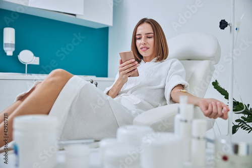 Obraz na płótnie Happy smiling woman sitting in medicine armchair during medical procedure in beauty center w salonie