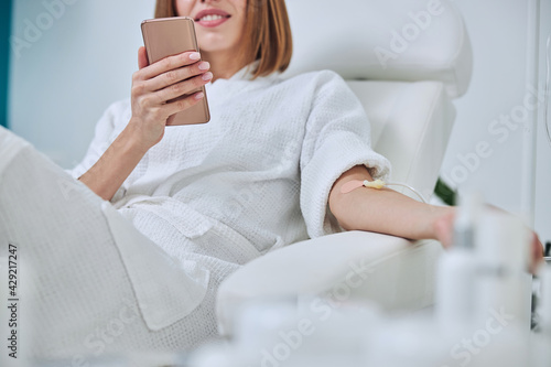 Beautiful Caucasian woman sitting in armchair during medicine procedure in spa salon photo