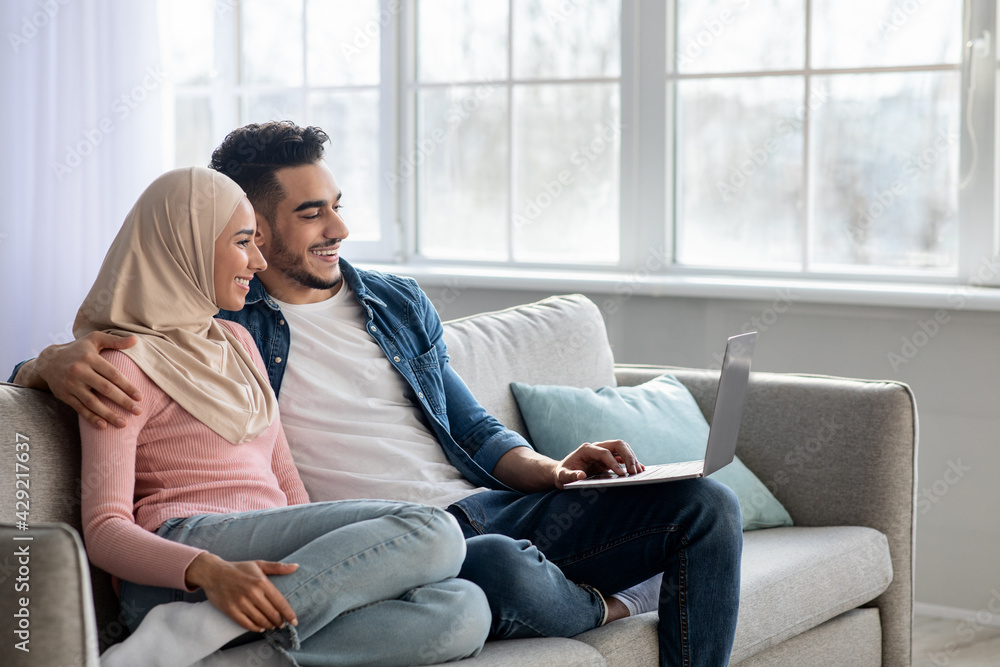 Fototapeta premium Happy young muslim family using laptop together at home
