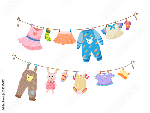 Baby fabric apparel. Baby girls and boys clothes hanging on clothesline. Drying children clothes and accessories after washing on rope. Shorts, socks, sweater, hat, toys, T-shirt, sarafans