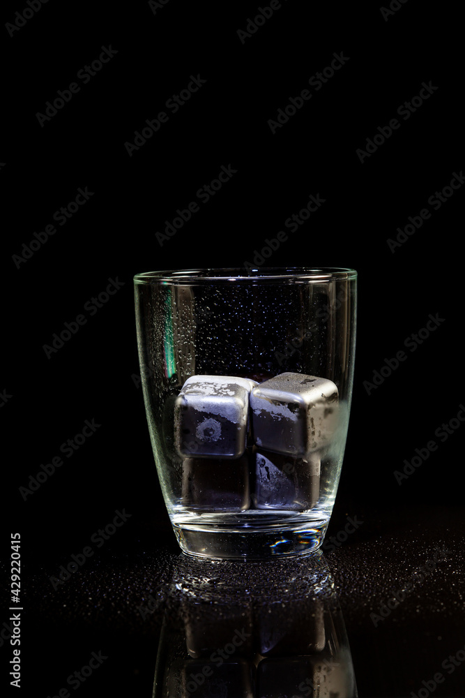 stainless steel cubes simulating ice in whisky glass on a black table. stainless steel cubes simulating ice in whisky glass on a black table.