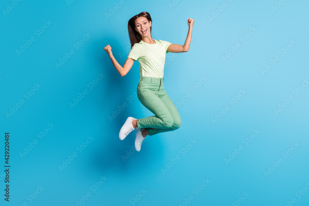 Full length body size photo of pretty girl gesturing like winner jumping high laughing isolated on vibrant blue color background